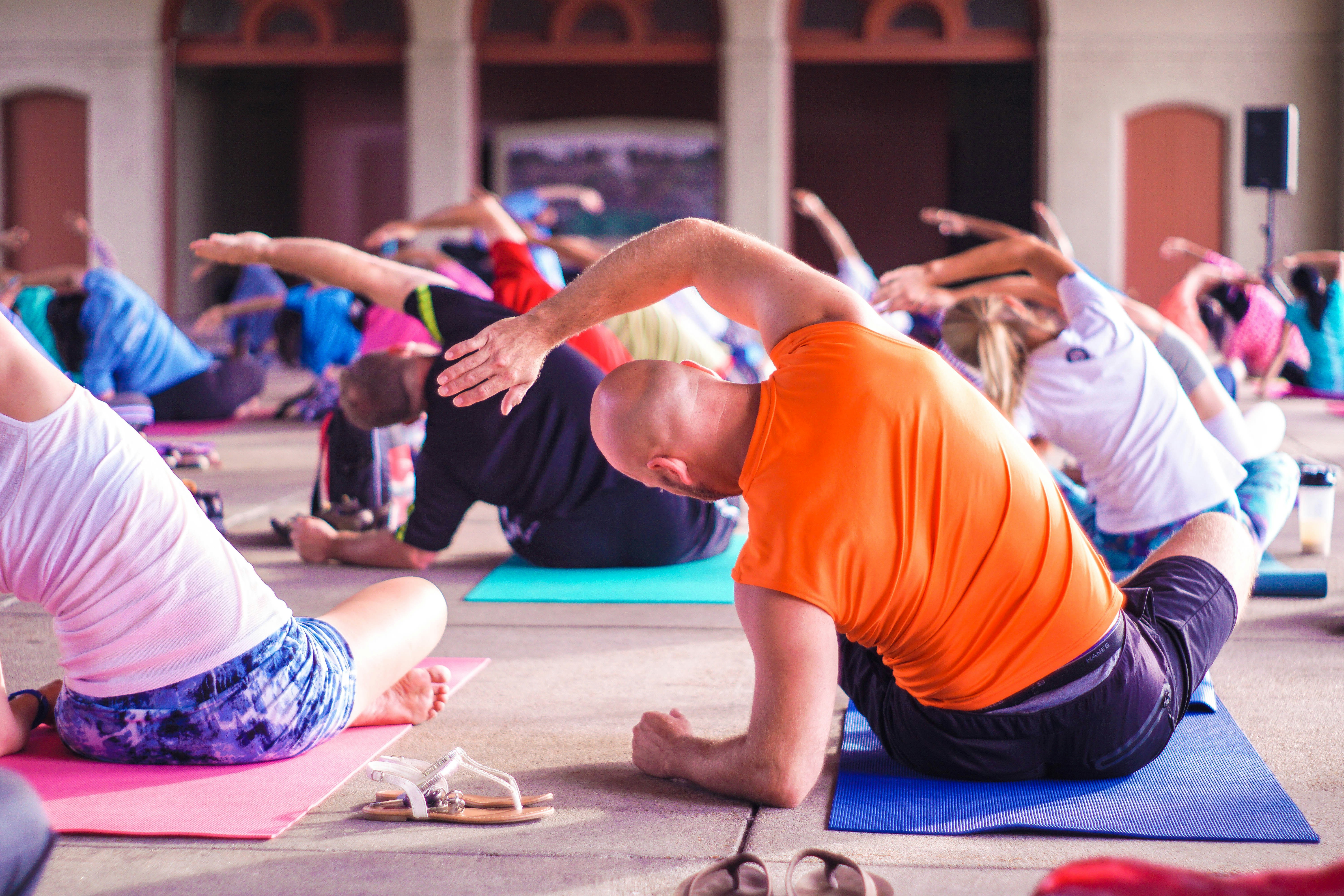 A group of people sitting in an open hall attending a Yoga Class