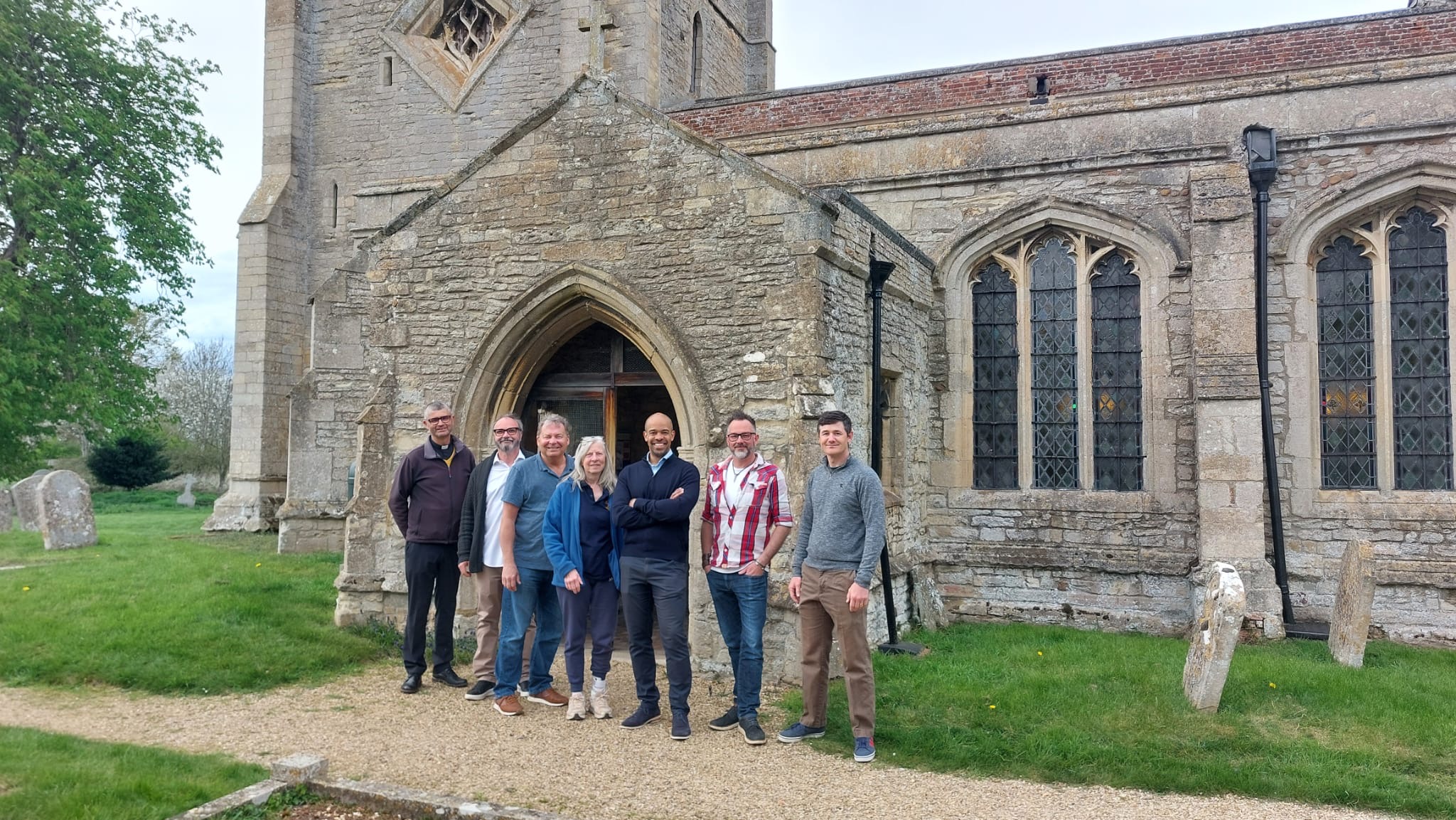 Photo of Ben Obese-Jecty and Spaldwick Common Ground Committee standing at the entrance of St James Church Spaldwick